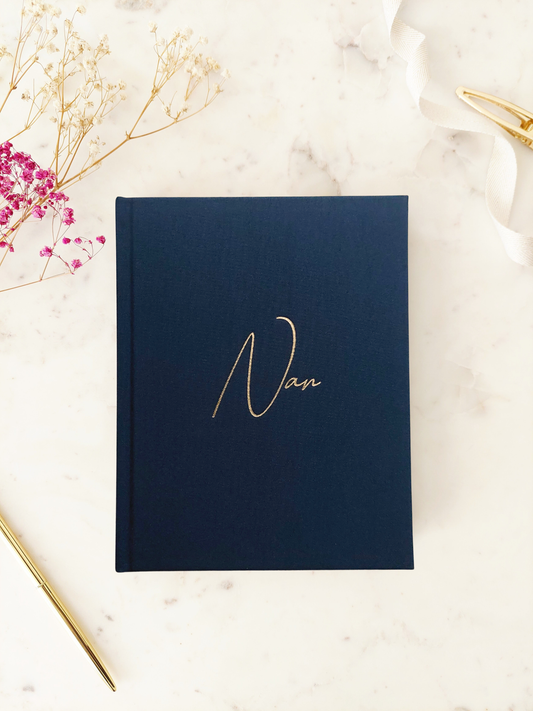 Navy journal with 'nan' written in gold font, displayed on a table